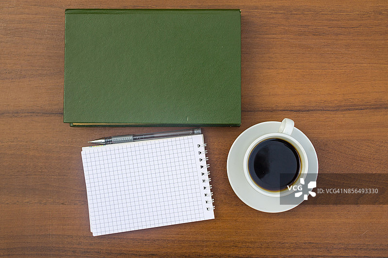 咖啡杯，书，记事本和笔放在木桌上图片素材