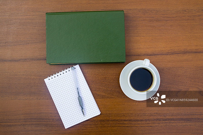 咖啡杯，书，记事本和笔放在木桌上图片素材