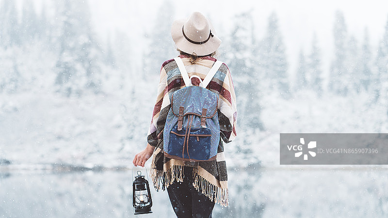 女旅人拿着煤油灯在雪湖边欣赏风景图片素材