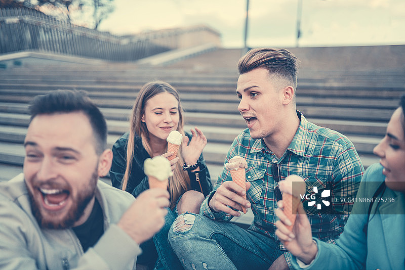 微笑的青少年朋友在城市的楼梯上吃冰淇淋图片素材