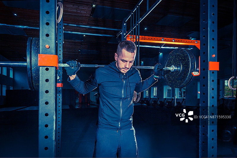 肖像超级健康的肌肉年轻人在健身房锻炼杠铃图片素材