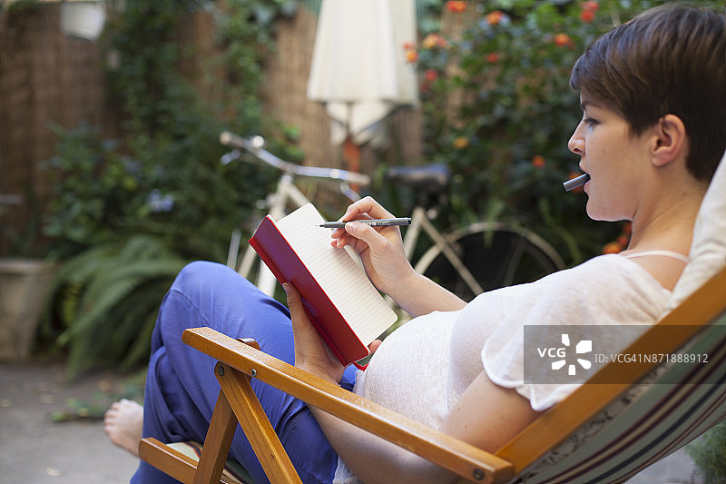 孕妇躺在躺椅上，写日记图片素材