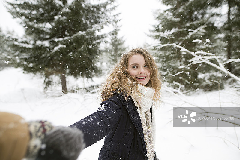 肖像的幸福年轻女子牵手在冬天的森林图片素材
