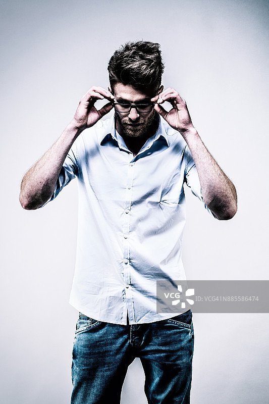 年轻人站在白衬衫，脸，手戴眼镜图片素材