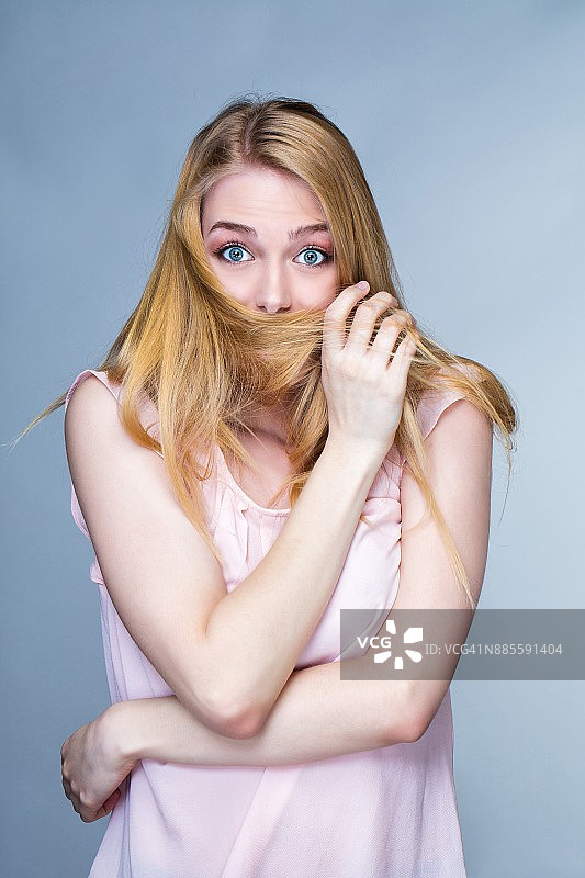 一个惊讶的年轻女人的肖像，头发在嘴巴前面图片素材