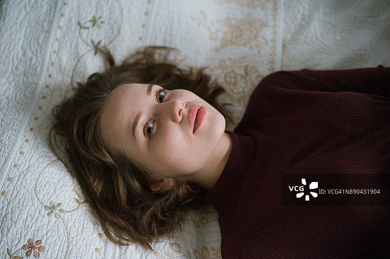 一个躺在床上的年轻女人的肖像。图片素材