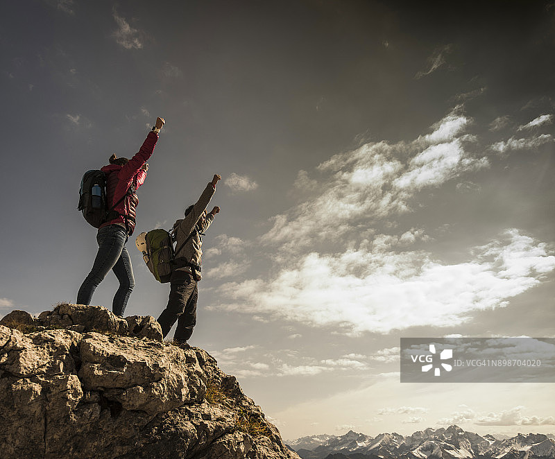 德国，巴伐利亚，奥伯斯特多夫，两个徒步旅行者在高山风景的岩石上欢呼图片素材