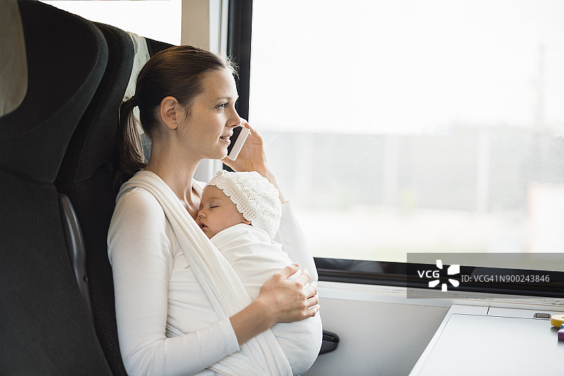 母亲和女婴乘火车旅行时，正在打手机图片素材
