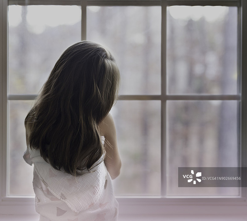 一个棕色长发的年轻女孩正看着窗外图片素材