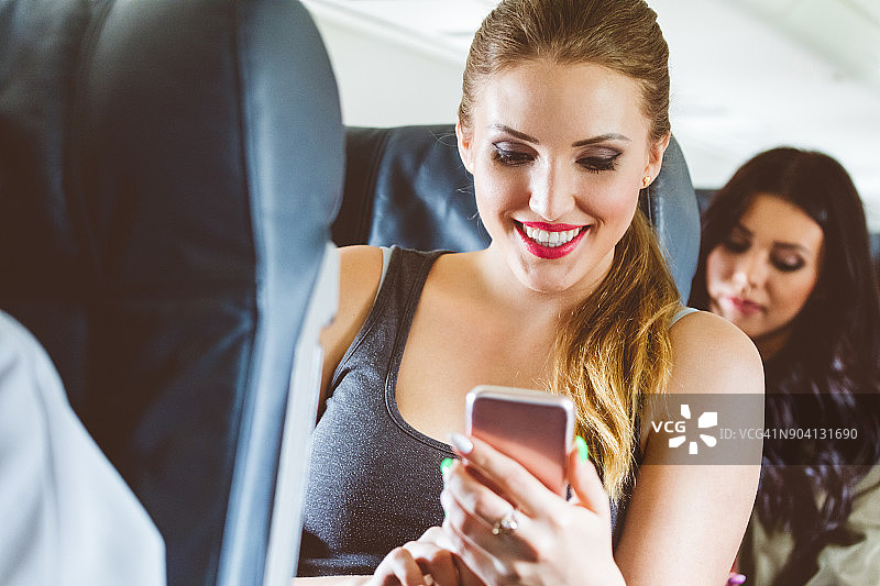 一名年轻女子在飞行中使用智能手机图片素材