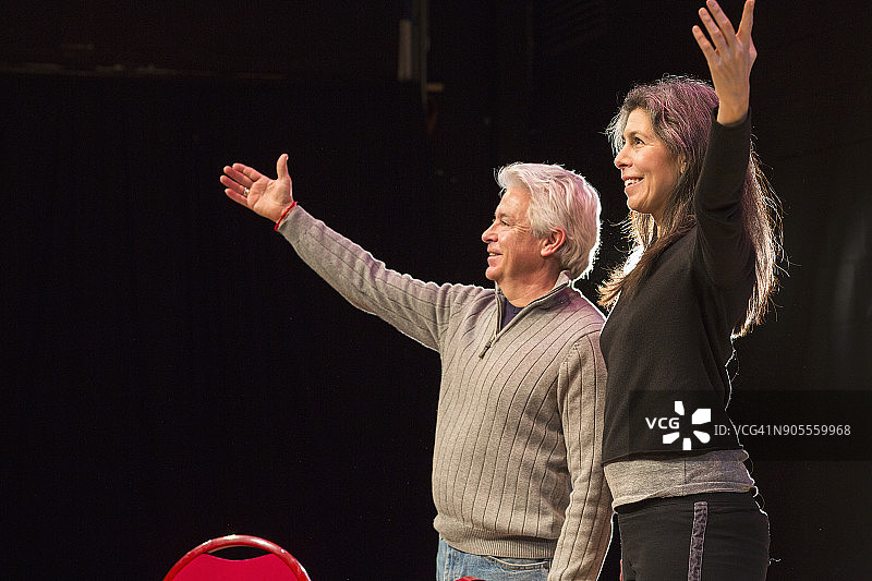 西班牙裔男人和女人在舞台上举起手臂图片素材
