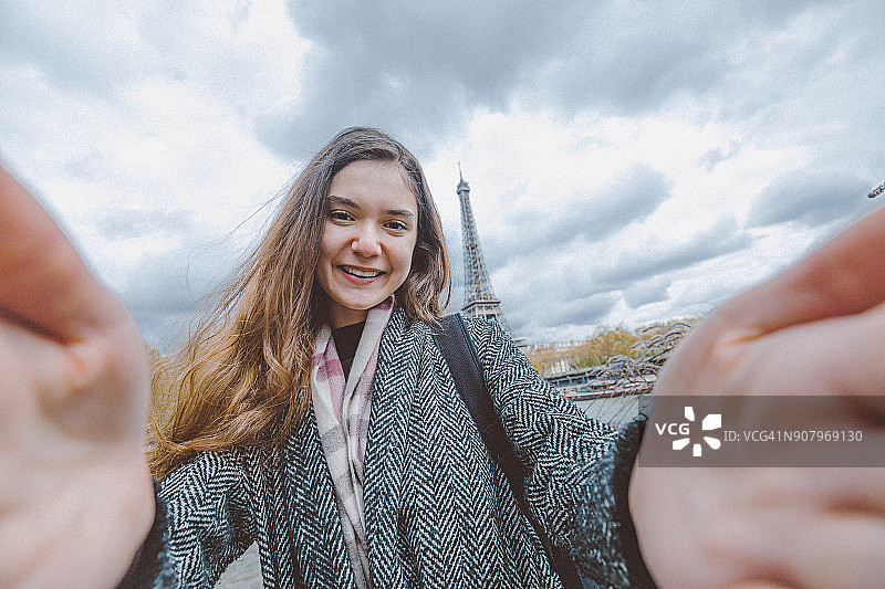 年轻女子用智能手机对着埃菲尔铁塔自拍图片素材