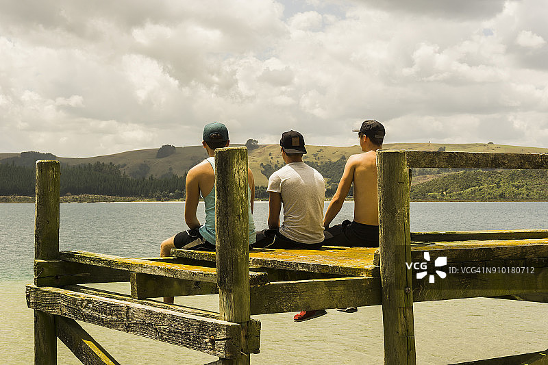 三个朋友坐在码头上的后视图图片素材