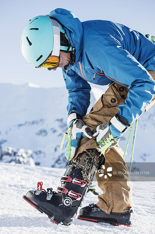 成熟的男人穿上滑雪服，穿上滑雪靴图片素材