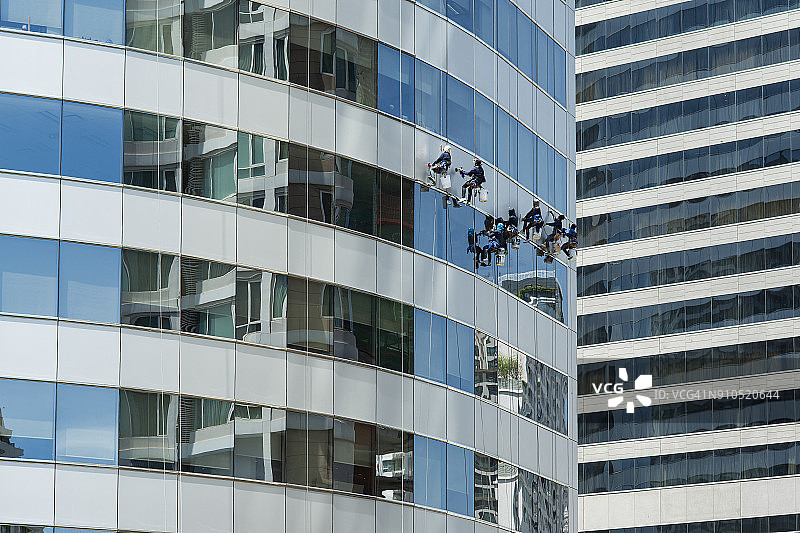 工人用吊索在高处清洁建筑物。高空作业安全设备。安全的概念。图片素材