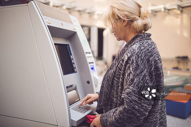 在ATM机输入密码的资深女士图片素材