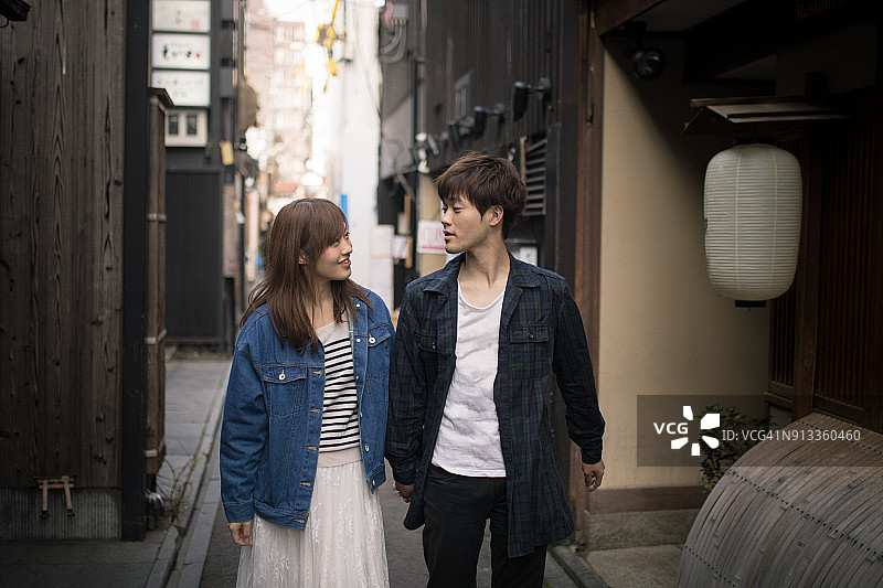 一对年轻的日本夫妇走在日本京都的蓬图町小巷上图片素材