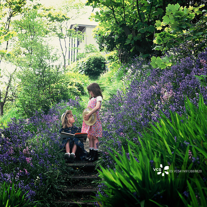 两个小孩在蓝铃花的花园里玩耍图片素材