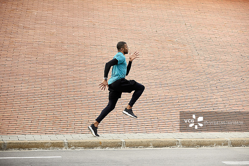 侧视图专注的运动员慢跑的墙壁图片素材