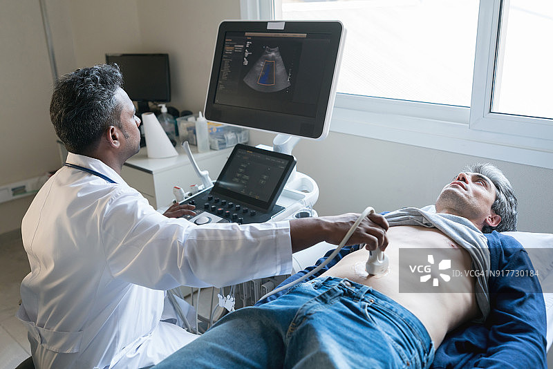 一位中东医生正在给一位中年男子做超声波扫描图片素材