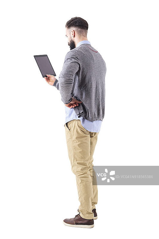 后视图时尚的现代商人手持平板电脑与手在臀部图片素材