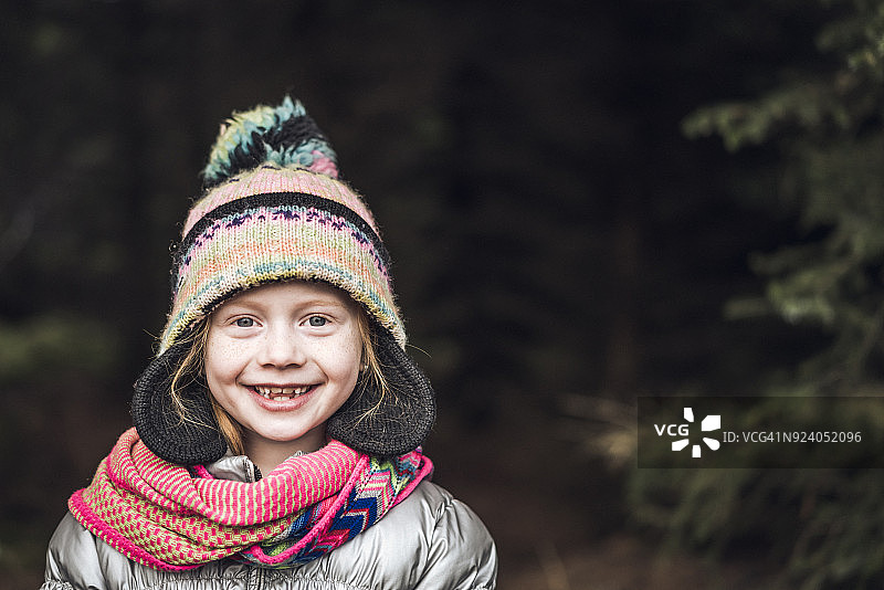 小女孩戴着针织帽在森林里微笑图片素材