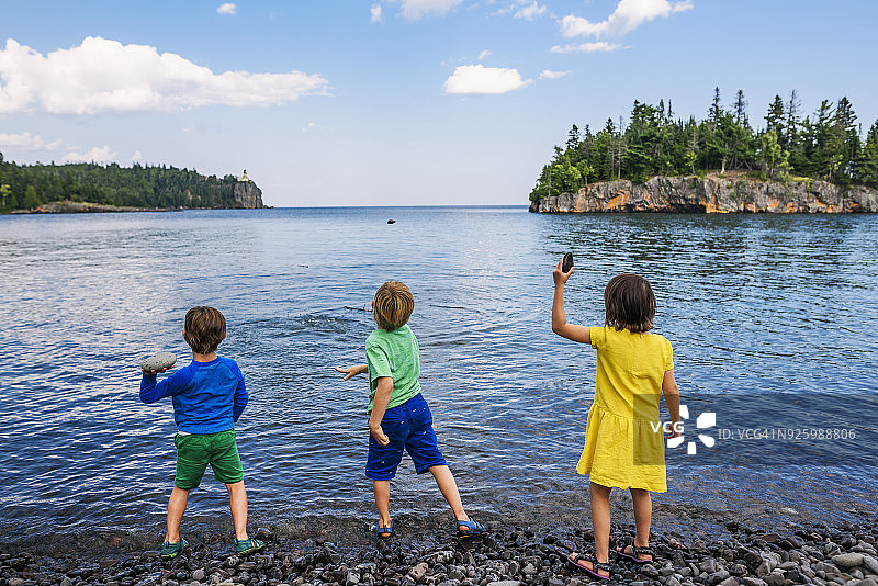 三个孩子往湖里扔石头图片素材