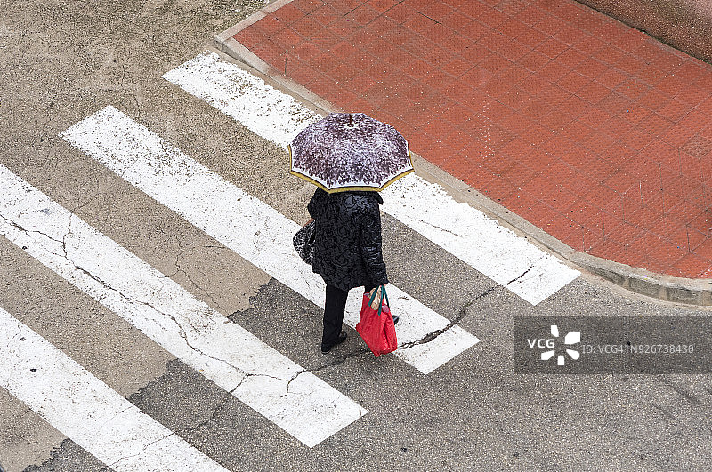 高角度的人与伞走在雨中的街道与购物袋。图片素材