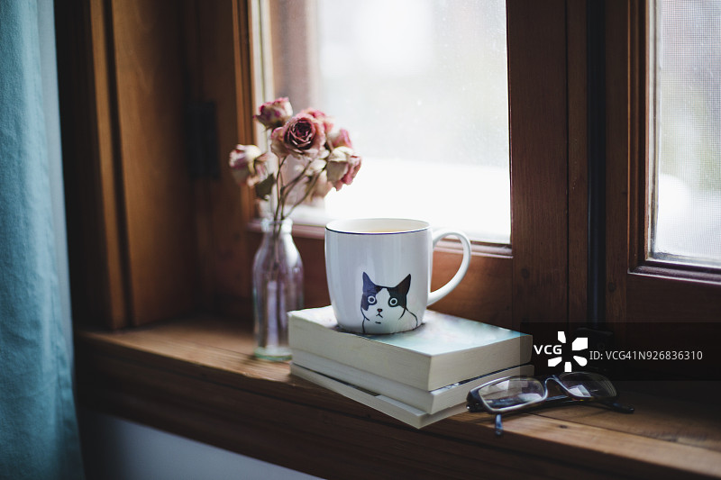 在窗台上放着干玫瑰的书上喝一杯茶图片素材