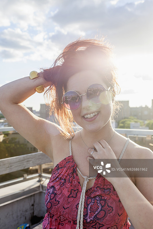 一个年轻女子在日落时戴着太阳镜的肖像图片素材