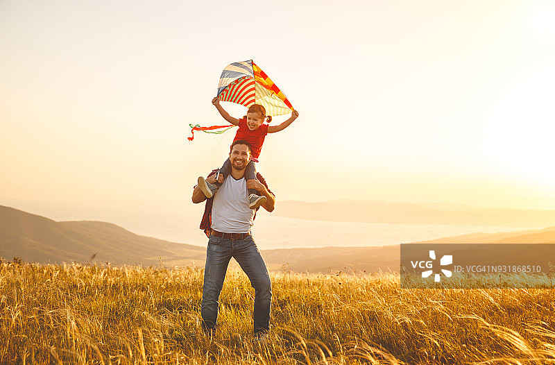幸福的家庭，父亲和孩子女儿在草地上追风筝图片素材