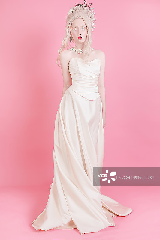 一个金发女人，有着美丽奢华的洛可可式发型，穿着白色的裙子，粉红色的背景。图片素材