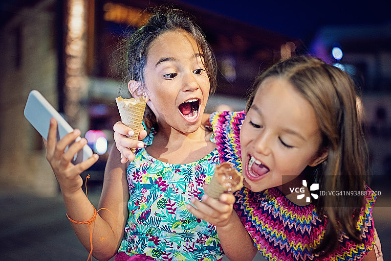 顽皮的女孩试图咬她姐姐的冰淇淋图片素材