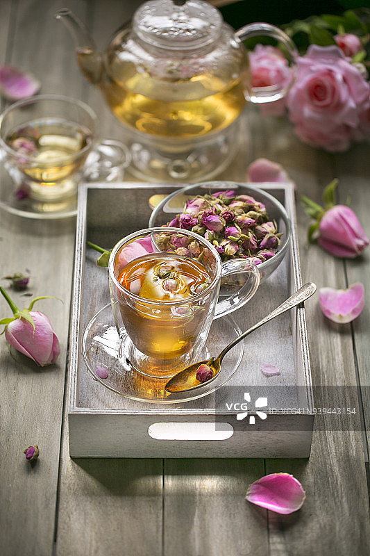 装饰杯中的玫瑰茶在木制桌面上。图片素材