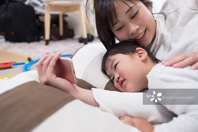 母亲和孩子躺着看智能手机图片素材