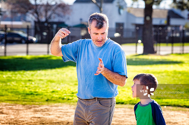 成熟的父亲向年幼的儿子解释棒球角度图片素材