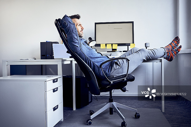一个人坐在办公室的办公桌前放松图片素材