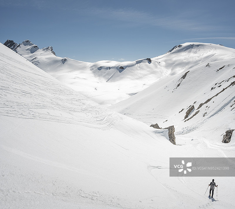 一个登山者站在白雪覆盖的雄伟山谷里图片素材