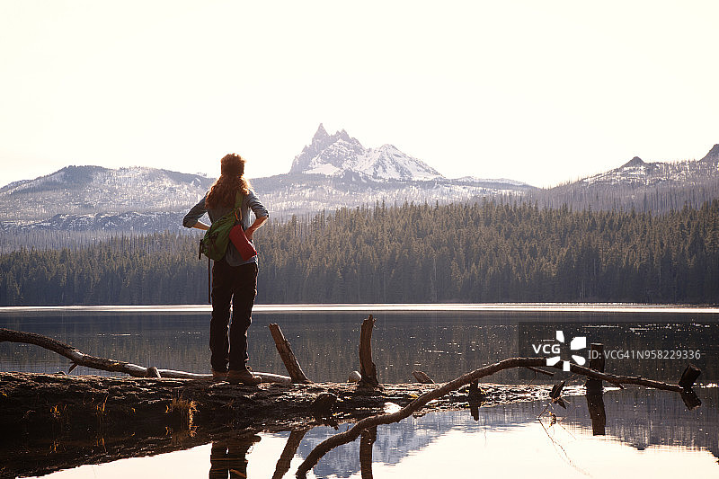 女徒步旅行者靠着山站在湖边图片素材