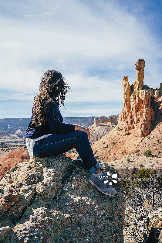 坐在沙漠岩石上看风景的女人图片素材