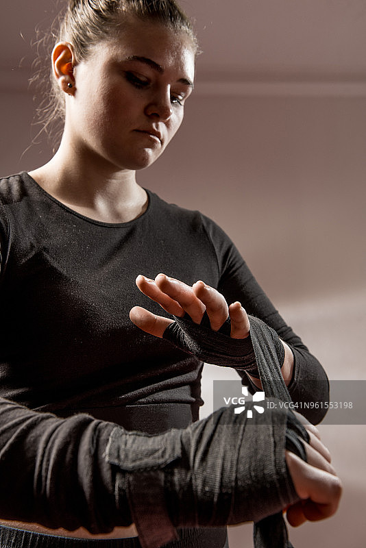 年轻女子拳击手在她的手腕上绑着保护绷带图片素材