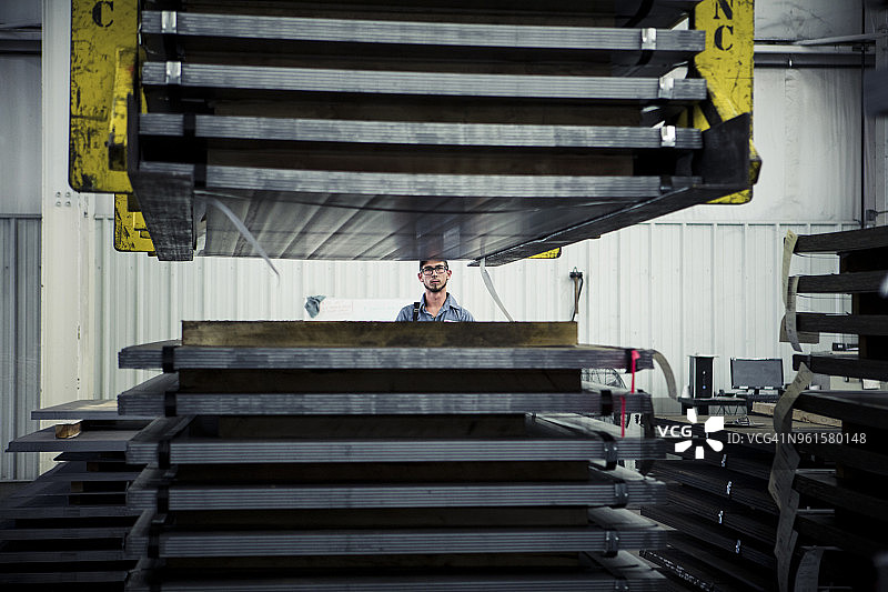 手工工人在工厂看着机器提升钢板堆垛图片素材