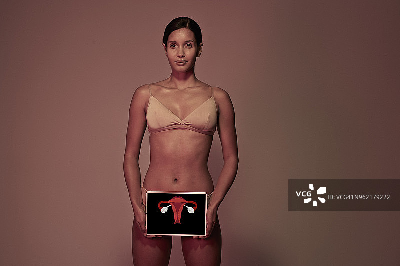 年轻女子拿着药片在身体前显示子宫和卵巢图片素材