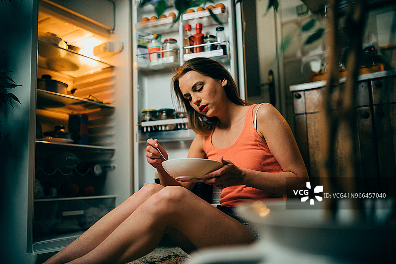 深夜在厨房冰箱前吃东西的女人图片素材