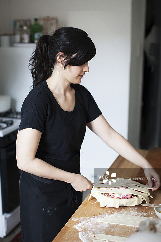 站在厨房柜台边准备大黄馅饼的女人图片素材