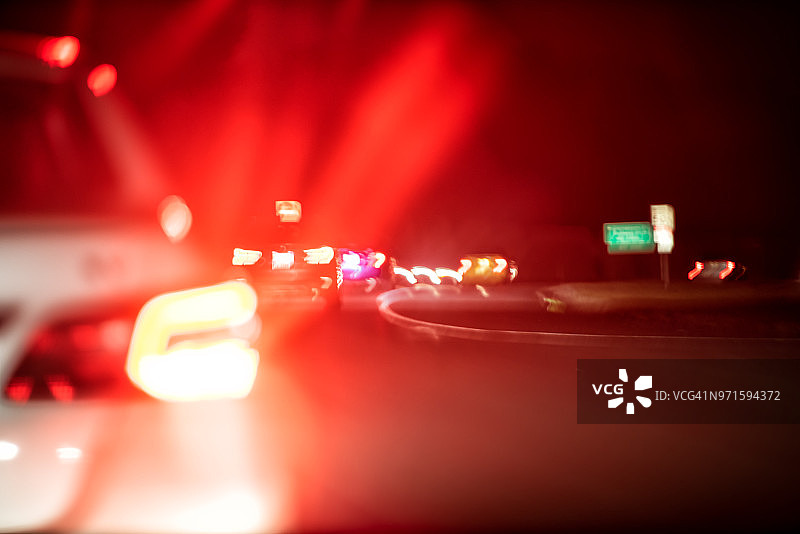 摘要特写许多车辆在黑暗的夜晚在交通中行驶，傍晚五颜六色的颜色，街灯，红色的刹车形状图片素材