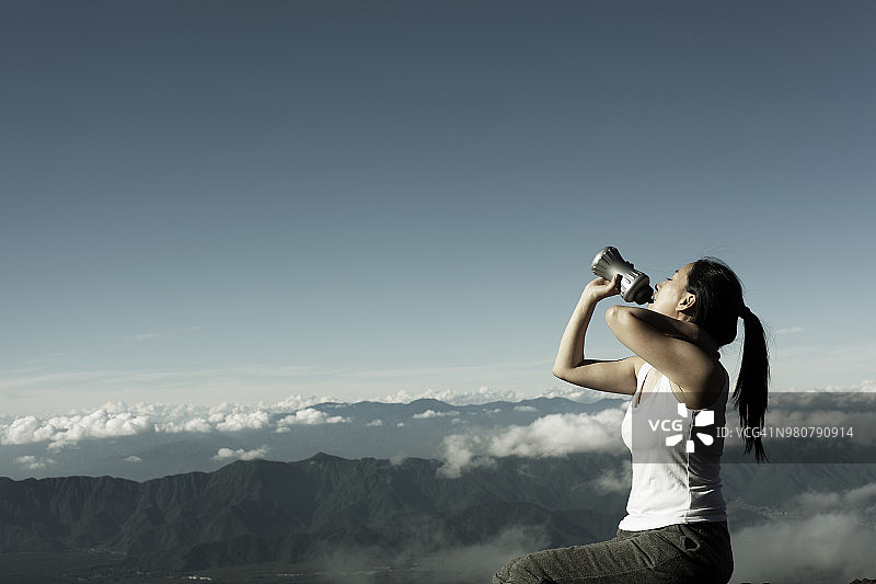 富士山上喝瓶子里的水的年轻女子图片素材
