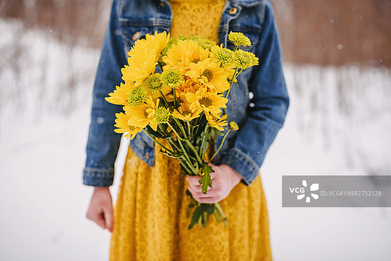 一个女孩站在雪中拿着一束花的特写图片素材