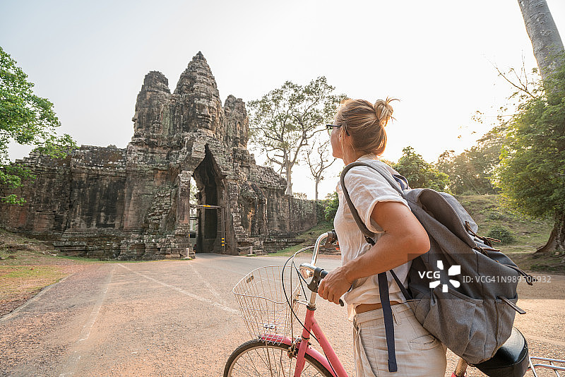 柬埔寨古庙建筑群里骑自行车的年轻女子图片素材