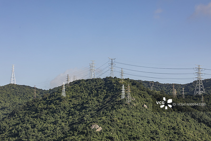在一个阳光明媚的日子，山上有许多高压电塔图片素材